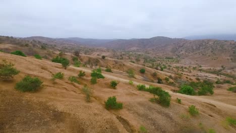 aerial view of cyclist on a dirt road through arid mountains
