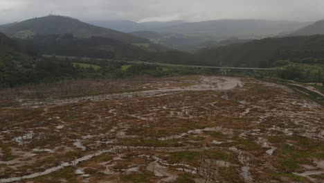 Wide-frontal-view-of-road-bridge-over-wetland-area,-mountain-shrouded-in-clouds