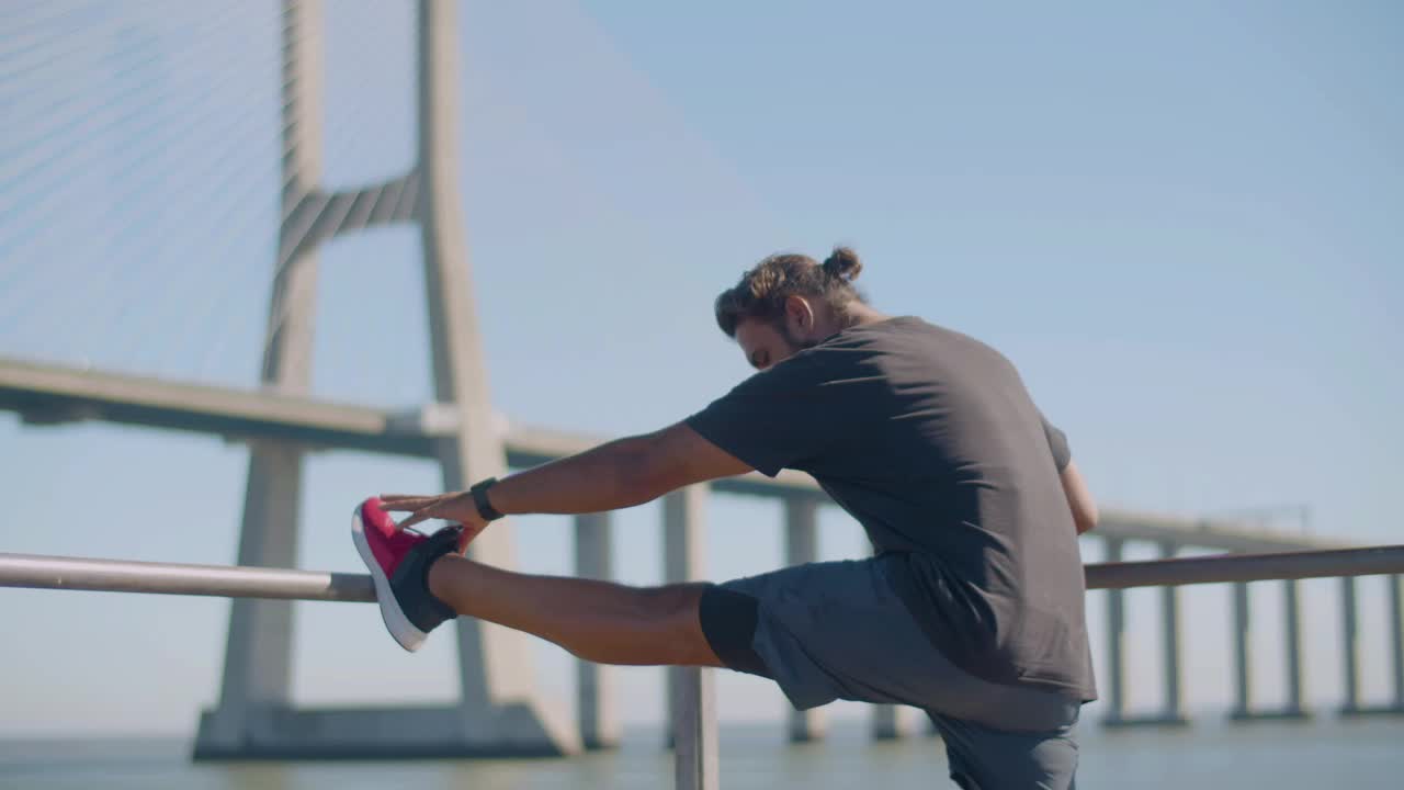 Male athlete performing stretching exercise outdoors.
