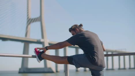 male athlete performing stretching exercise outdoors.