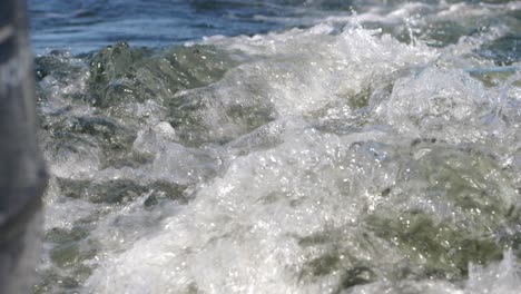 blue ocean wake foam moving behind boat motor in slow motion, shallow depth of field