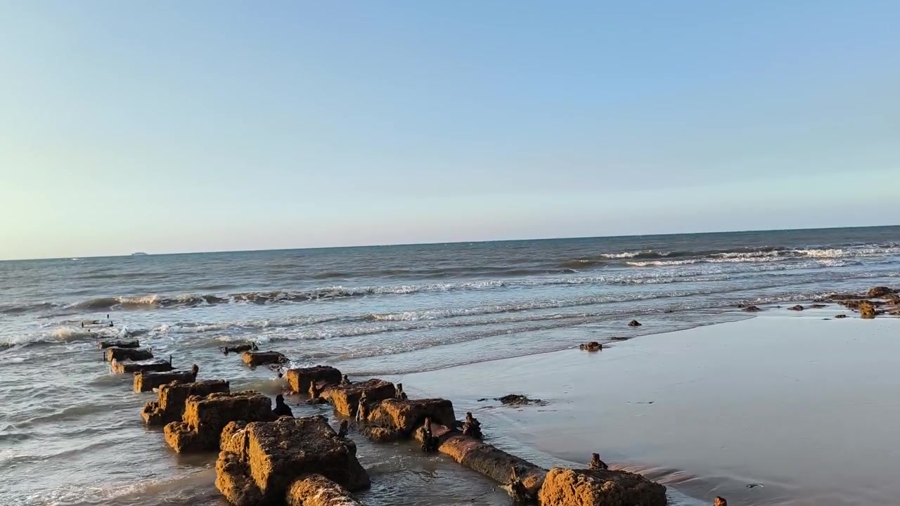 Waves Gently Rolling onto a Sandy Beach with Old Concrete Pillars