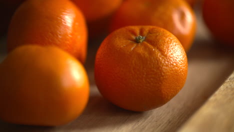 slow motion footage of fresh, ripe clementines dropping and rolling on a wood cutting board