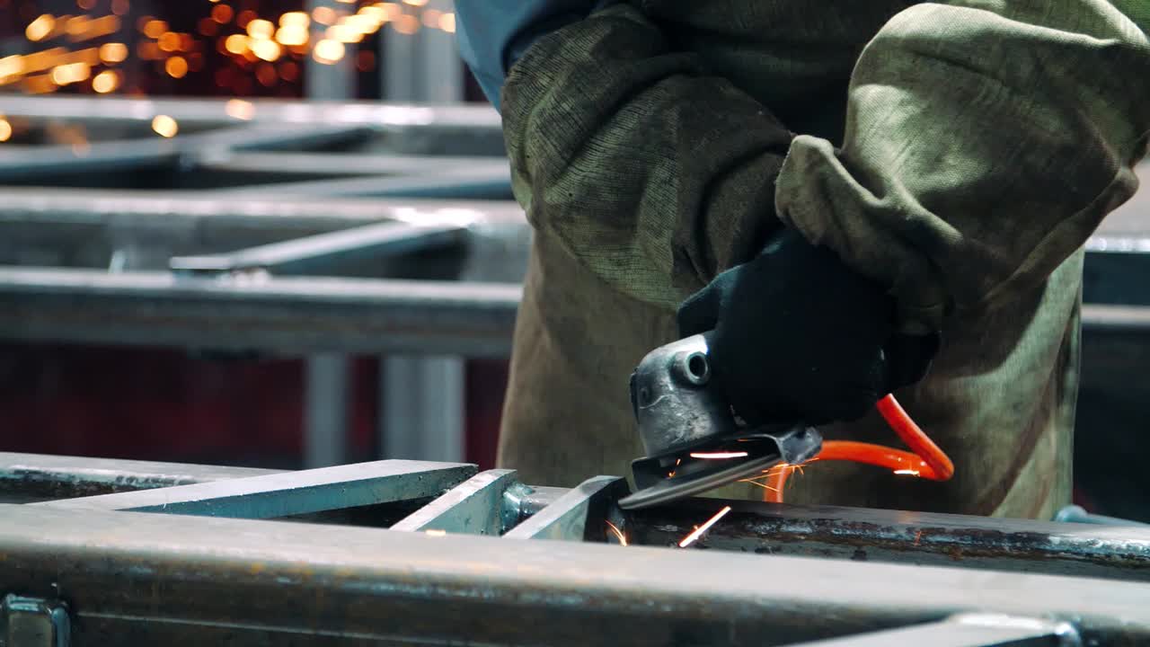 Sliping av sveisesømmer med vinkelsliper ved en fabrikk. Bruk av industriverktøy.