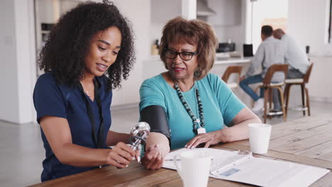 Female-healthcare-worker-checking-the-blood-pressure-of-a-senior-woman-during-a-home-visit