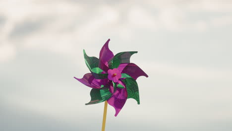 close up of colourful pinwheel rotating vigorously under cloudy sky motion blur capturing whimsical movement and soft ambient light against overcast backdrop