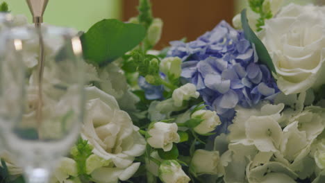 an elegant visual detail where the initial focus shows glass cups on the table and, through gentle panning, it blurs to focus on a delicate floral arrangement.
