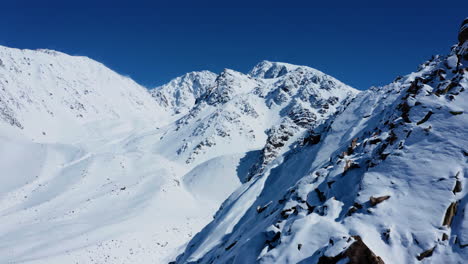 Antena---Cumbres-Nevadas-Y-Pistas-De-Esquí-Bajo-Un-Cielo-Azul-Profundo,-Adelante