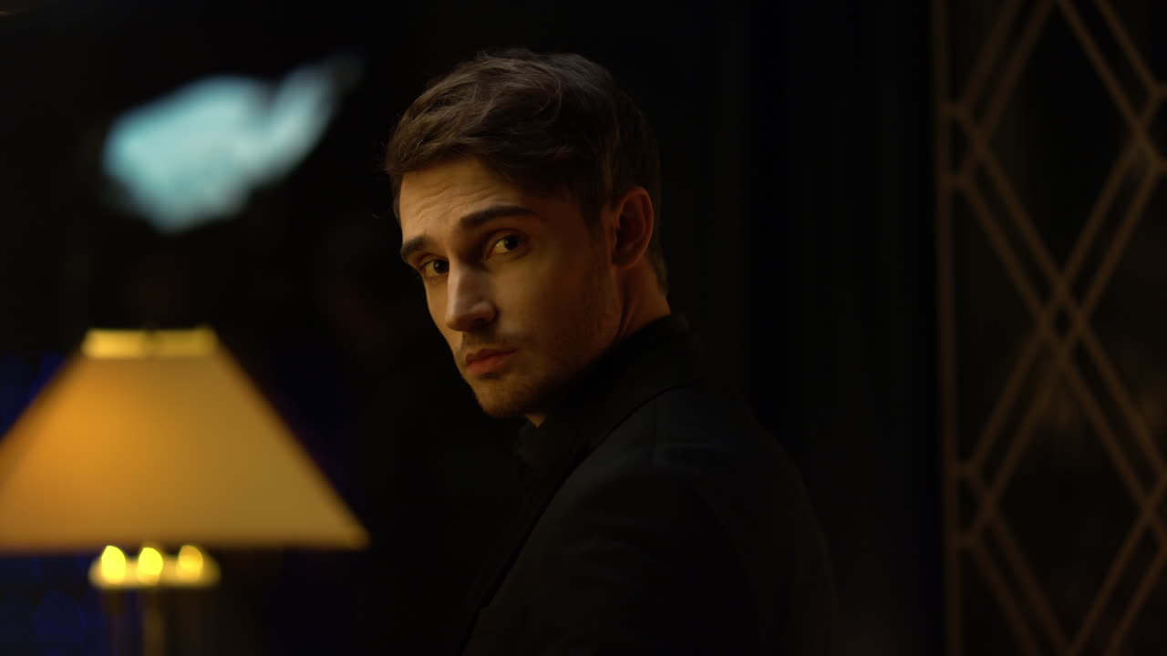 어두운 방에 서 있는 세련된 남자.