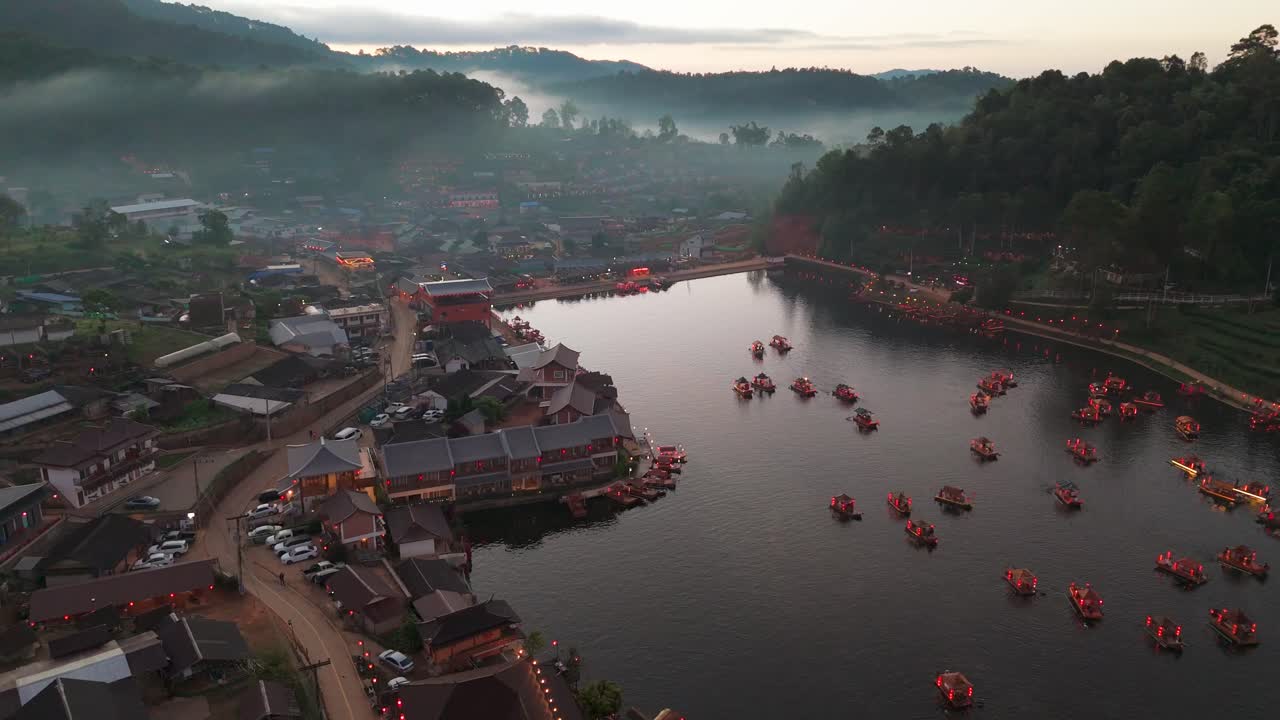 dolly aéreo de ban rak thai, mae hong son, tailandia, con barcos en el lago y los exuberantes paisajes montañosos con niebla
