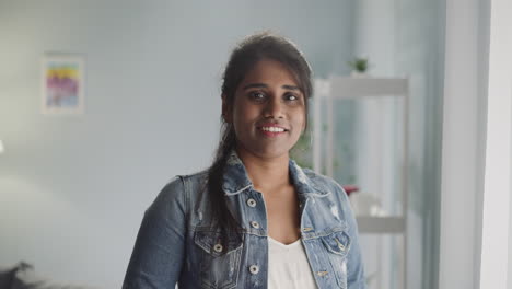 Friendly-Indian-woman-with-ponytail-looks-in-camera-smiling