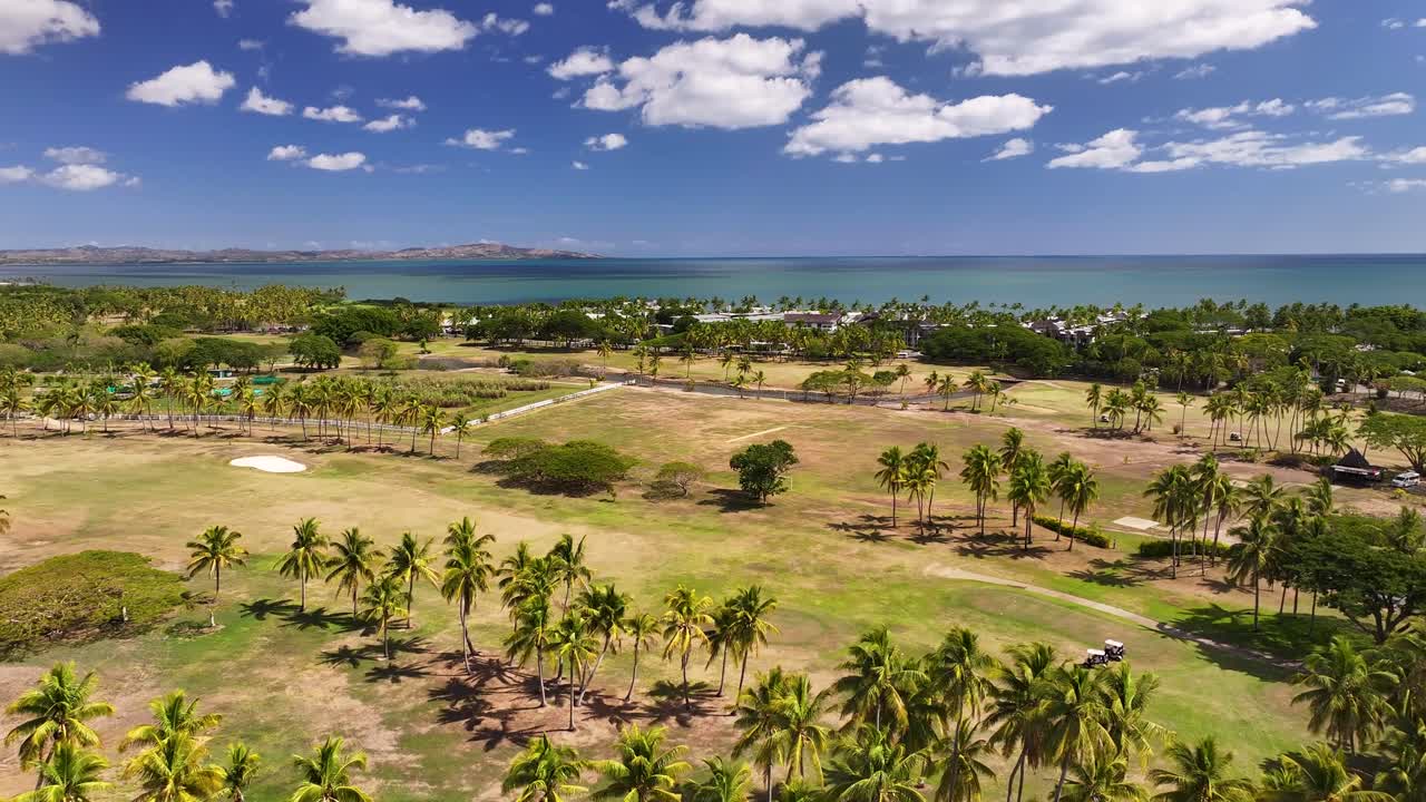 Drone fly over golf course with palm trees in exotic Fiji, Denarau Island. Summer sport activity.