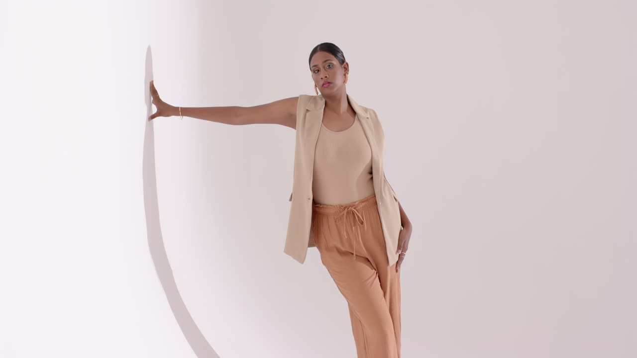 Entering studio triggers Indian woman posing with circular arch prop, adjusting blazer during shoot