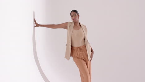 entering studio triggers indian woman posing with circular arch prop, adjusting blazer during shoot