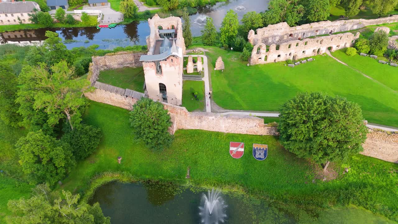 Aerial View of Dobele Castle Ruins, Flowing Berze River and Illuminated Fountains at Sunset Serene Latvian Summer Evening from Above, Scenic Aerial of Latvian Historical Landscape in Golden Hour