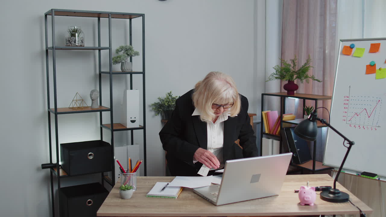 Ældre forretningskvinde undersøger grafer, analyserer og administrerer finansielle dokumenter/rapporter på hjemmekontoret