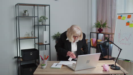 Senior-business-woman-examining-graphs,-analyzing,-managing-finance-documents-report-at-home-office