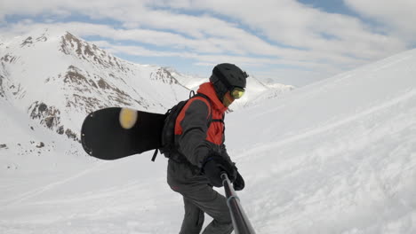 young male freeride snowboarder walking up snow covered hill, caucasus mountains, selfie