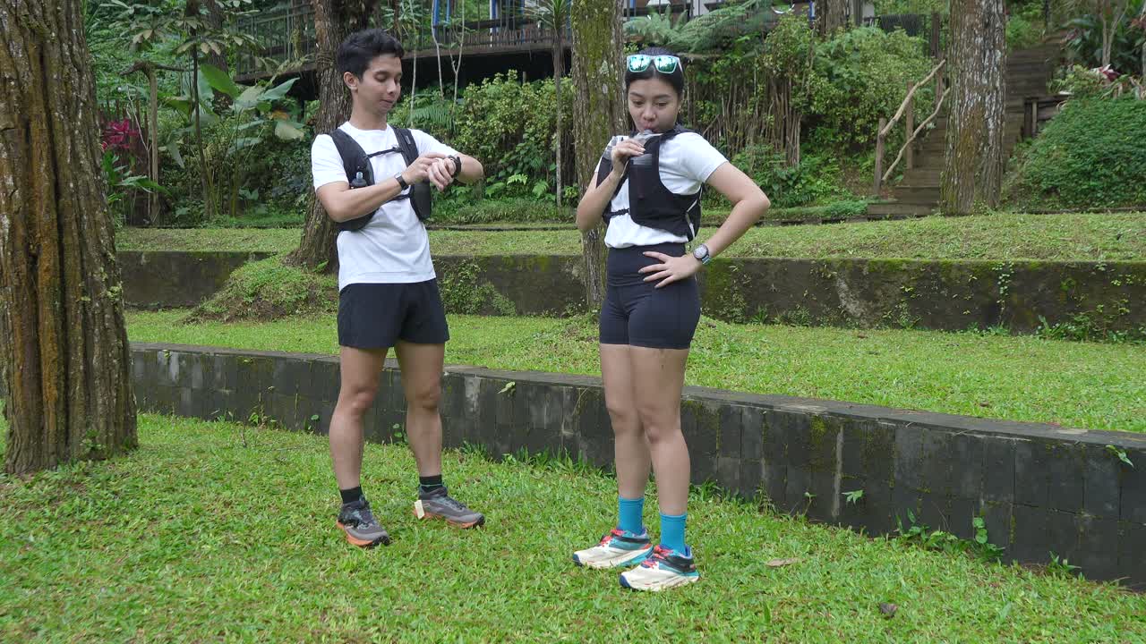 Asian couple resting and talking during outdoor workout in forest trail