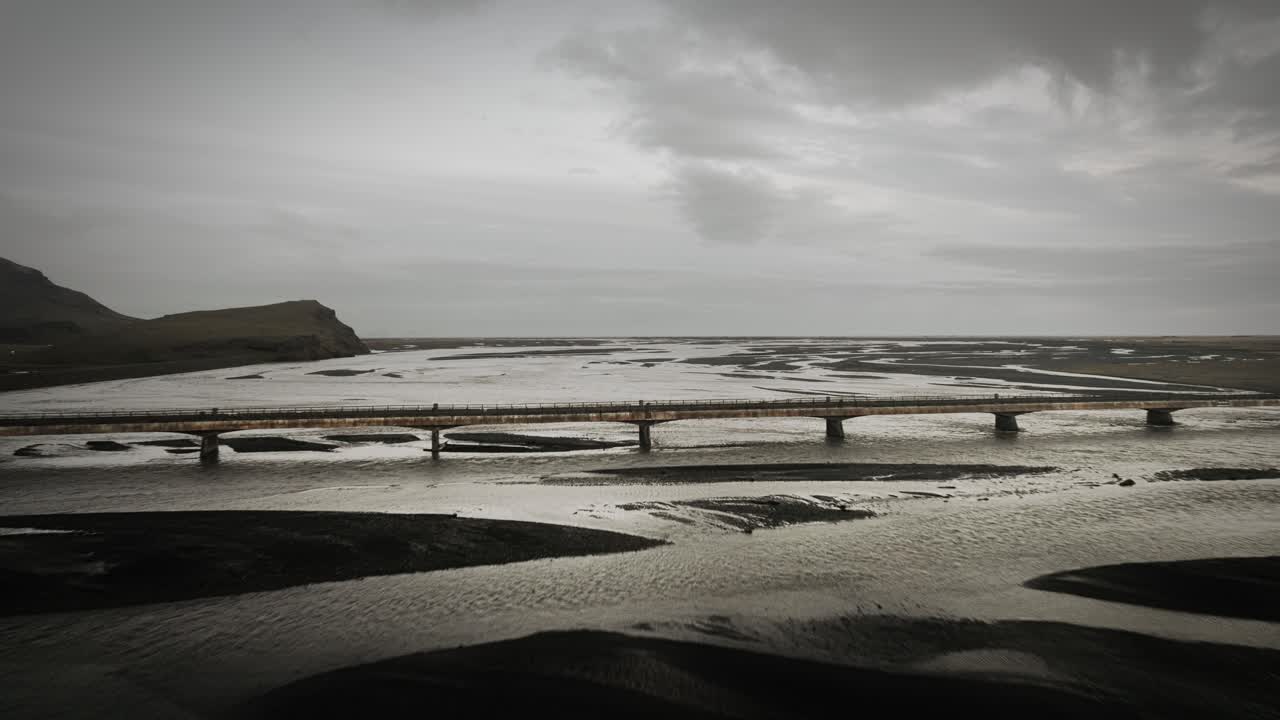 vuelo aéreo: puente que conduce sobre el lecho glacial del río en islandia vista del paisaje