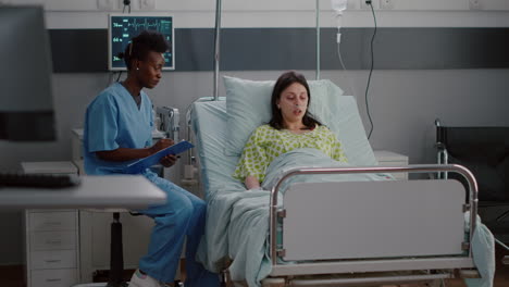 afro-american nurse discussing with sick woman monitoring illness symptom