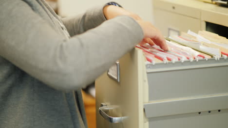 woman removes file from filing cabinet