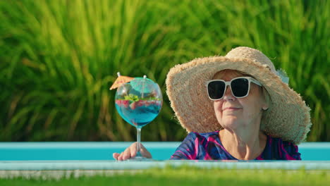 mujer mayor relajándose junto a la piscina con un cóctel