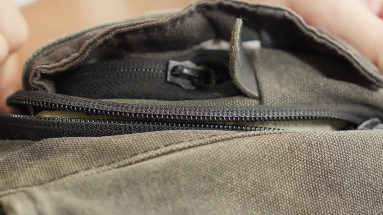 Close-up of the zipper of a bag, hands in action