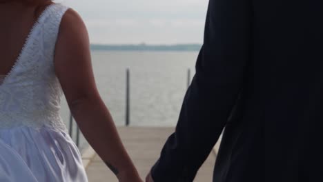 Freshly married couple walk into frame and hold hands, no faces