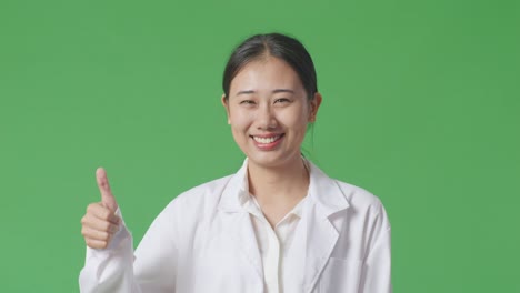 smiling asian woman in lab coat giving thumbs up