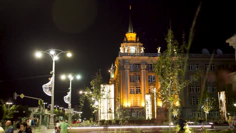 night view of a city plaza with an illuminated building and people