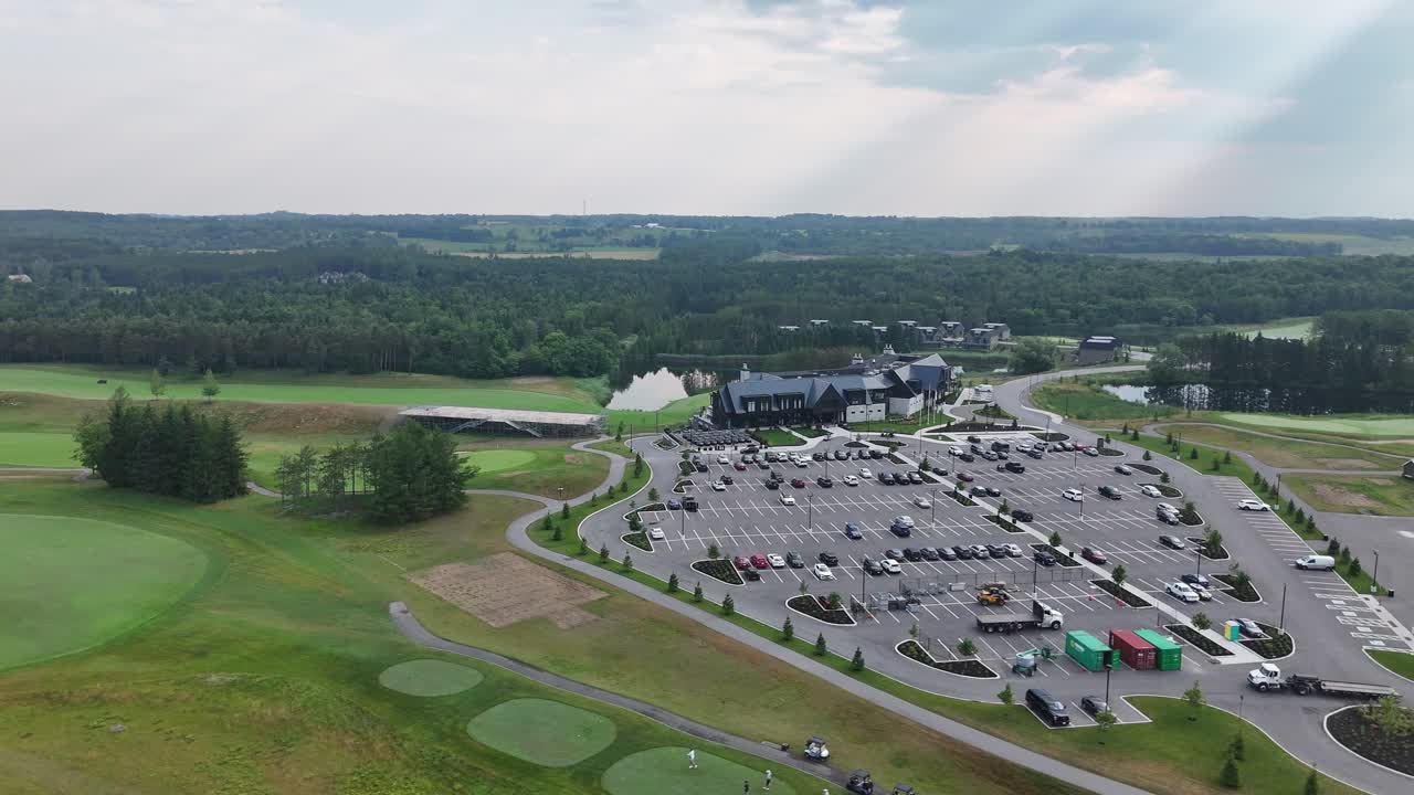 Aerial of expansive golf course with manicured greens, trees, and water features in sunlight