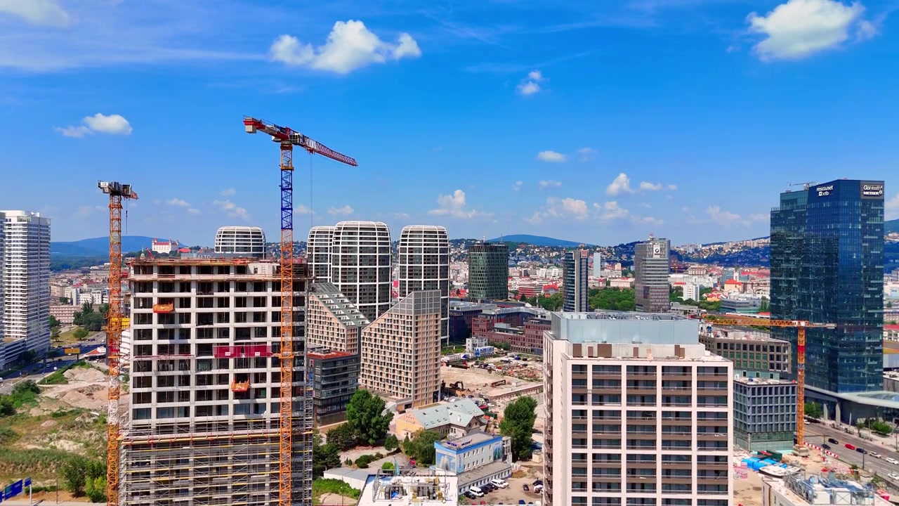 Bratislava, Slovacchia, 2 giugno 2026: Vista aerea della costruzione di un grattacielo a Bratislava. Inquadratura dall'alto di un'alta gru gialla in funzione vicino a moderne torri residenziali a molti piani durante il giorno