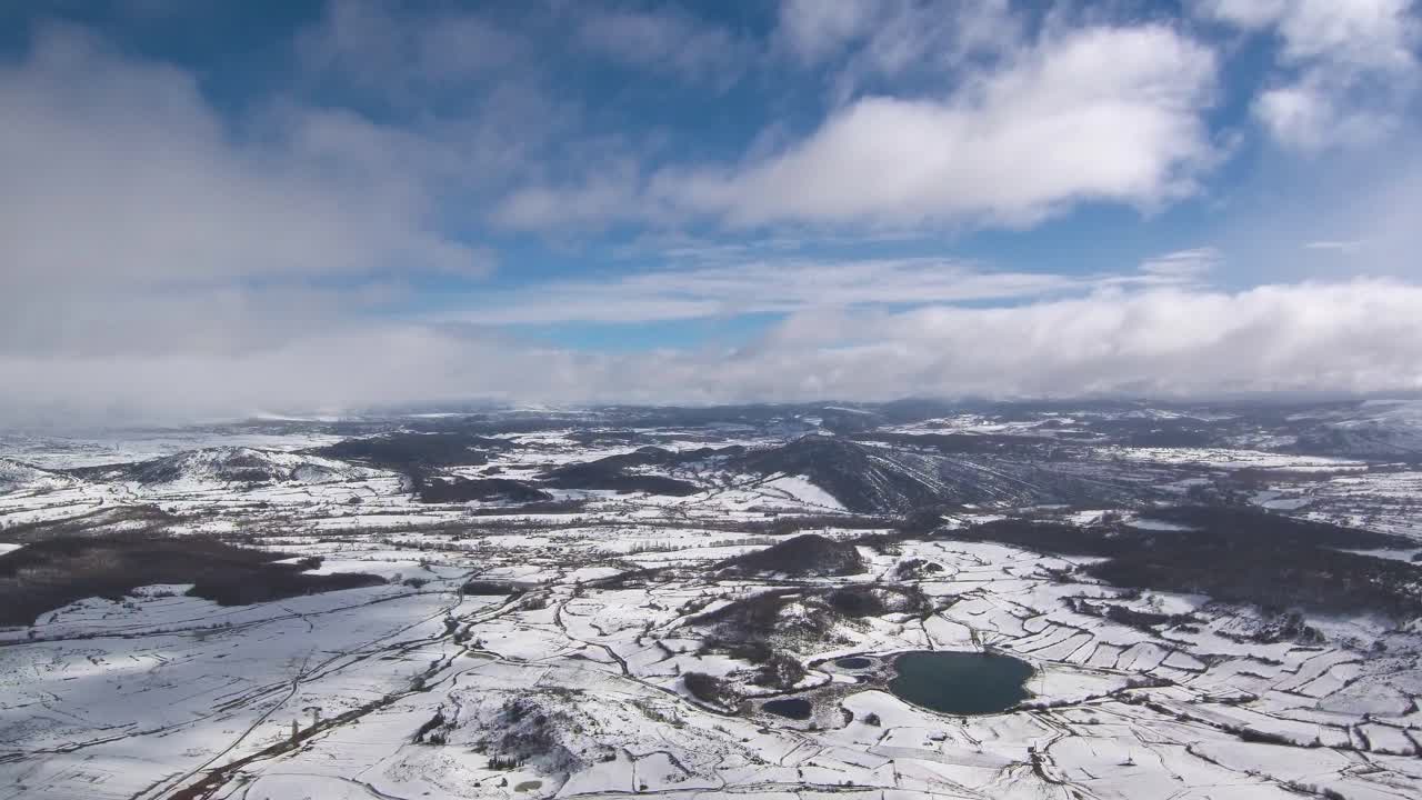 雪の日に山々を映した映像。大きな湖と村も見えます。