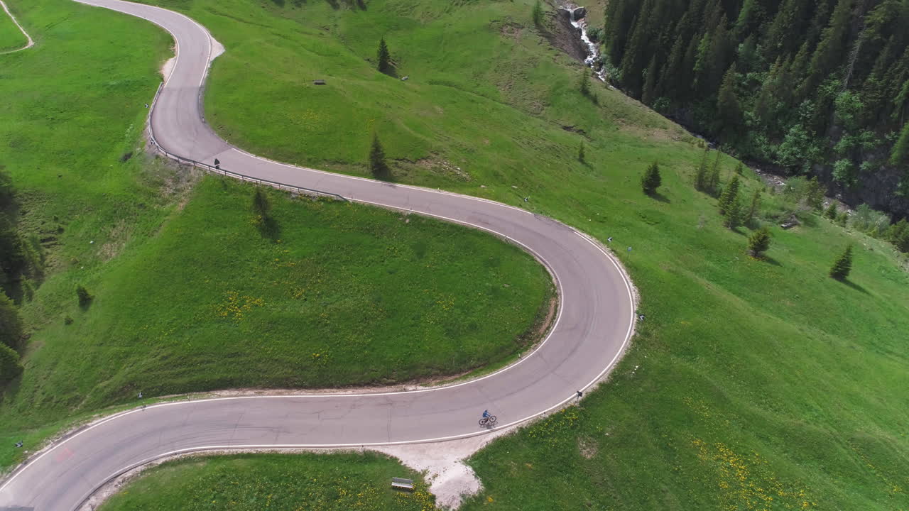 Cyclist Riding on a Twisty Road in a Field in the Dolomites, Italy, from a Drone