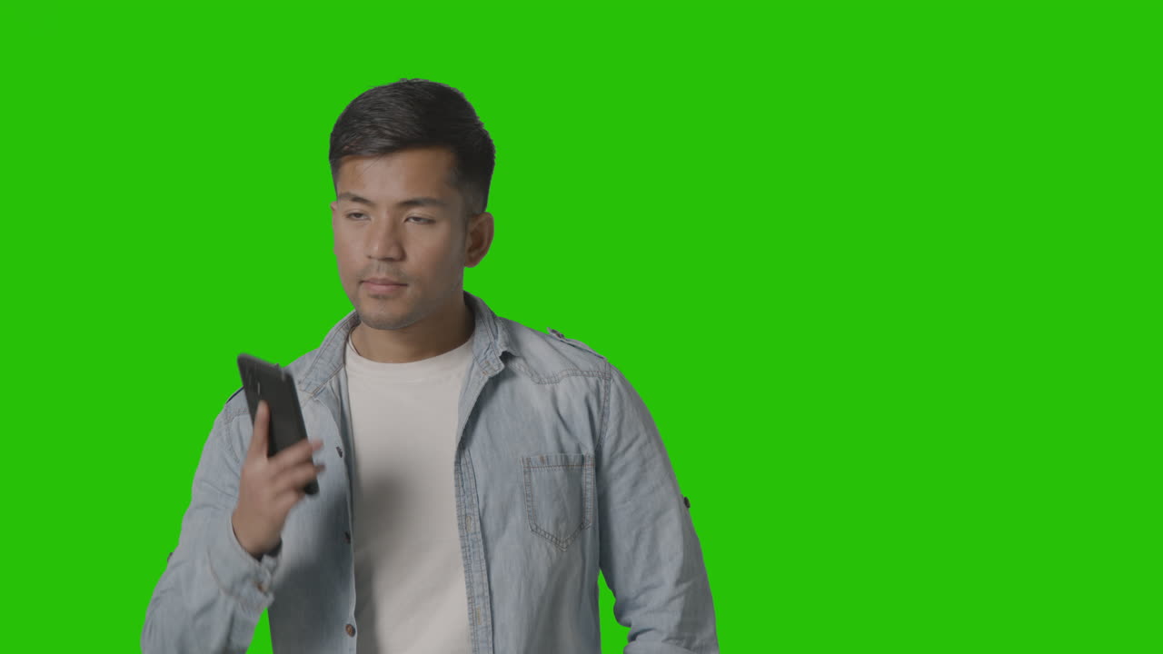 녹색 화면 1에 대 한 휴대 전화에 대 한 얘기 캐주얼 옷을 입고 웃는 젊은 남자의 스튜디오 샷