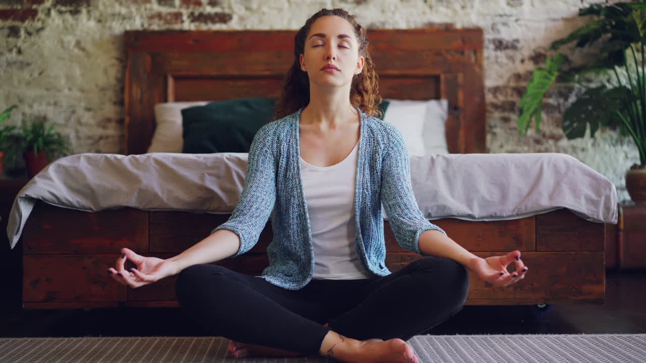 una mujer meditando en su dormitorio.