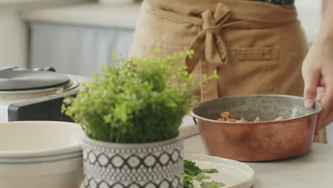 mujer de la cosecha poniendo nueces en el plato en la cocina