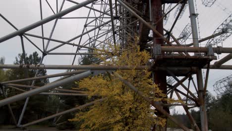 árboles otoñales bajo la estructura de acero oxidado de la antena duga en la estación de radar duga en la zona de exclusión de chernobyl en pripyat, ucrania