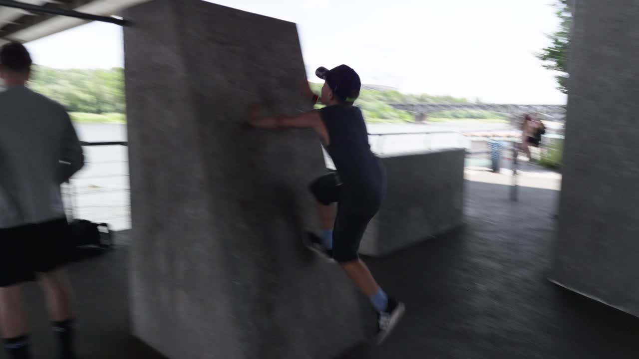 A boy tries to jump onto a concrete block in the outdoor fitness area under the War&scaron;avsk&yacute; Bridge