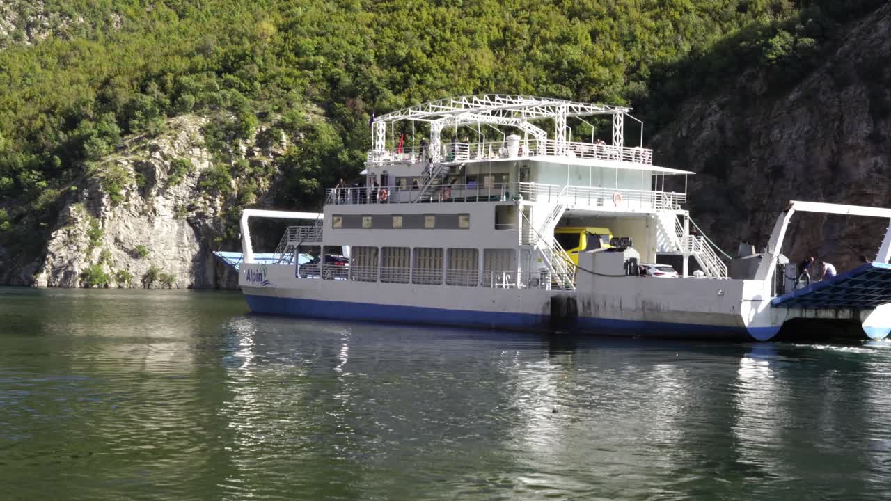 ferry saliendo de un pequeño puerto, llevando turistas que quieren visitar las altas montañas de los alpes en albania, los balcanes