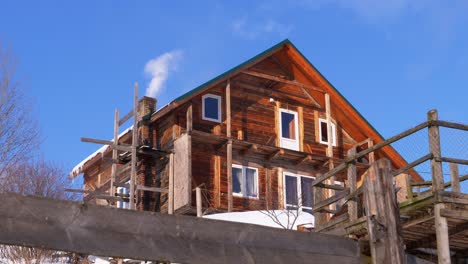 humo de una chimenea de ladrillo en un techo de casa de madera en invierno contra un cielo azul