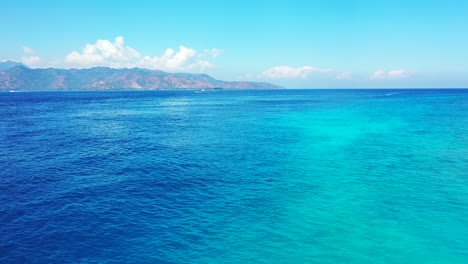 blue azure sea surface reflecting bright sky over volcanic mountain of tropical island in bali, copy space