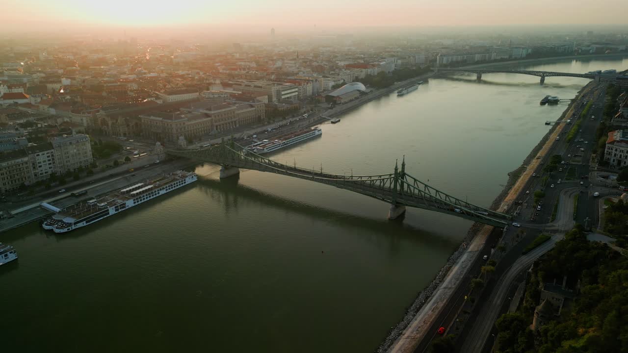 Sunset aerial over Danube bridges and Budapest Parliament with golden light on the water, estabilshing