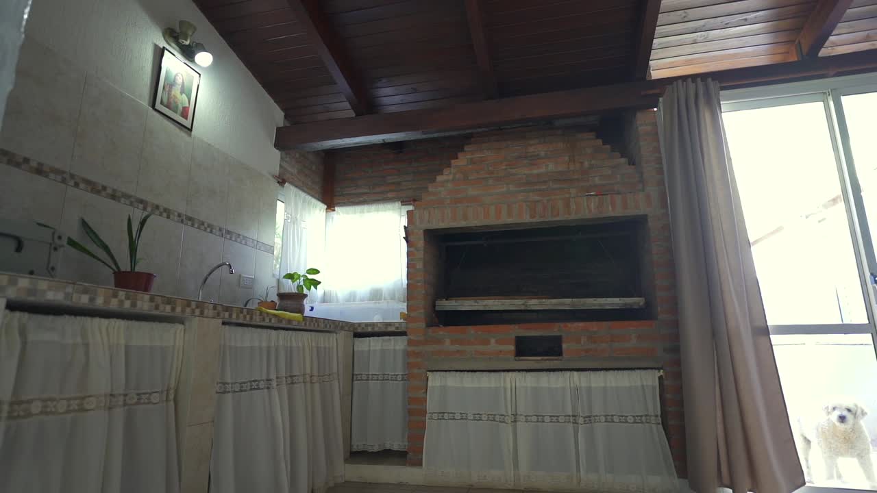 Indoor barbecue house grill kitchen area with brick grill and window in cozy rustic setting.