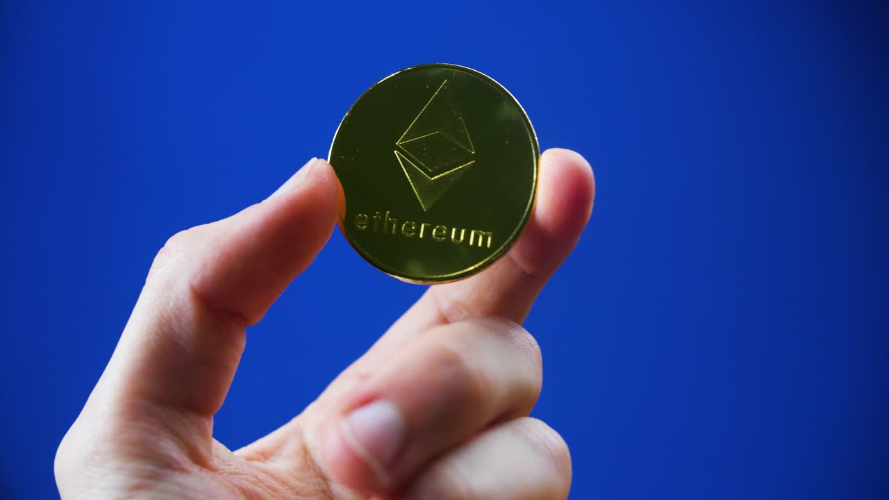 Hand holding an Ethereum coin on a blue background