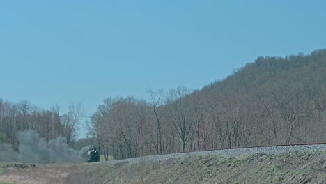 復元された狭いゲージの蒸気旅客列車が近づき ⁇ 春の日に煙と蒸気を吹き上げています ⁇