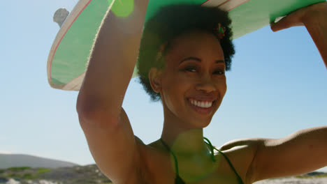 female surfer carrying surfboard on her head 4k