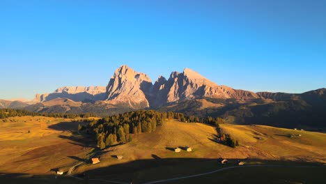 Mountains,-forest-and-grass-fields-with-wooden-cabins-filmed-at-Alpe-di-Siusi-inEuropean-Alps,-Italian-Dolomites-filmed-in-vibrant-colors-at-sunset