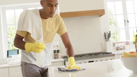 hombre biracial limpiando la encimera en una cocina brillante, cámara lenta